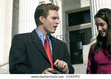 Young lawyer is talking over a case with his co-worker on the steps of the courthouse