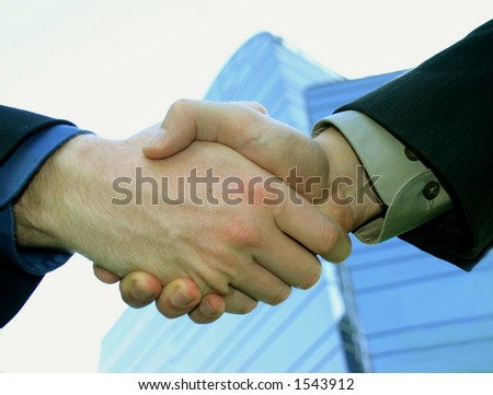 Business handshake in front of blue office building
