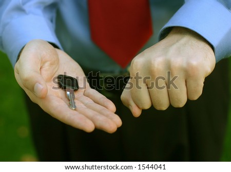 Businessman with blue shirt and red tie holds out both hands, one closed, and the other open with a key in the middle of his palm