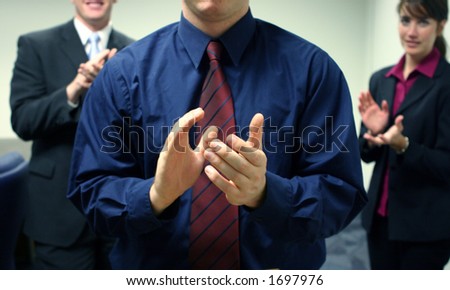 Business team of two men and one woman facing forward and clapping