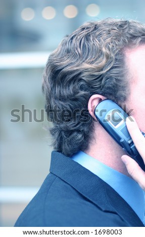 Business man holds up cell phone to his ear in front of business building