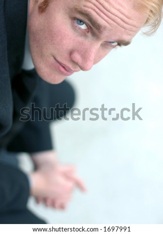 Business man with blond hair and blue eyes is looking up as he holds his hands - stock-photo-business-man-with-blond-hair-and-blue-eyes-is-looking-up-as-he-holds-his-hands-together-1697991