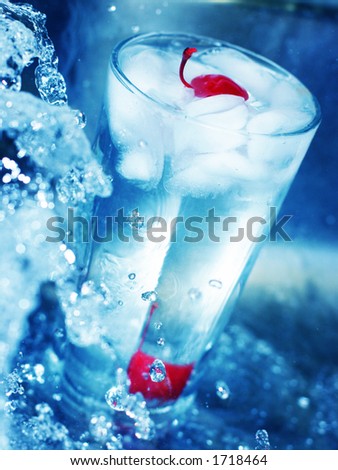 red cherry in glass of cool water around rushing water