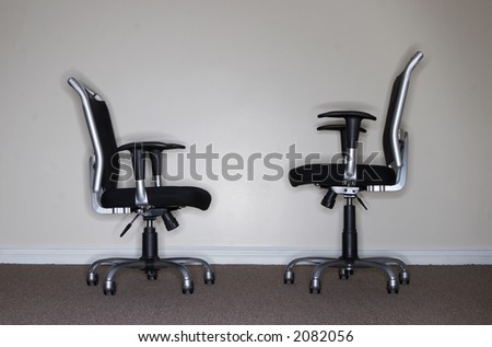 Two business chairs where one chair is looking at the other when which is taller