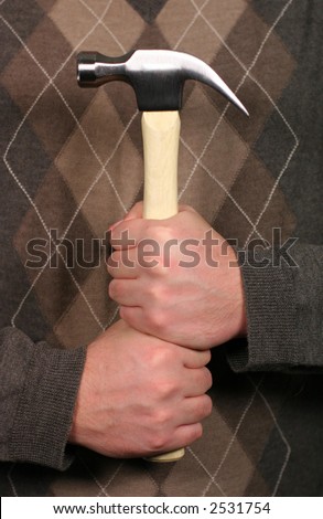 Man holding hammer with both hands in front of him while wearing a sweater in a sign of strength