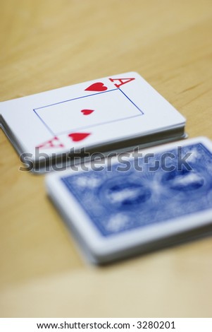 Deck of cards lying on a wooden table with the deck split in two and the ace on top