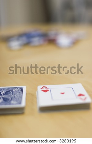 Deck of cards lying on a wooden table with the deck split and chips in the background