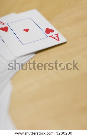 Deck of cards spread out on a wooden table with the Ace of Hearts side up