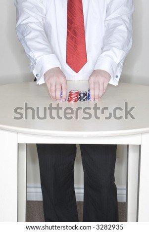 Man standing at a table holding some gambling chips in his hands