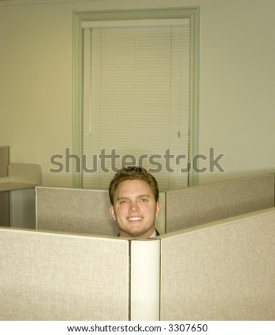 Businessman smiles and shows his head above the office cubicles