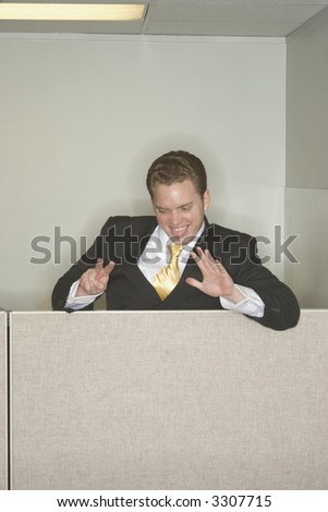 Businessman makes fun and laughs at his success holding up two of his fingers showing his ablities while looking down from the top of his other cubicle