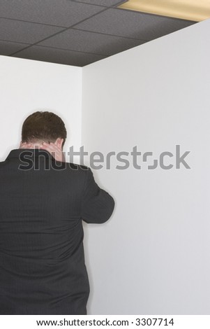 Businessman stressed out and stands in the corner in a white wall in the office