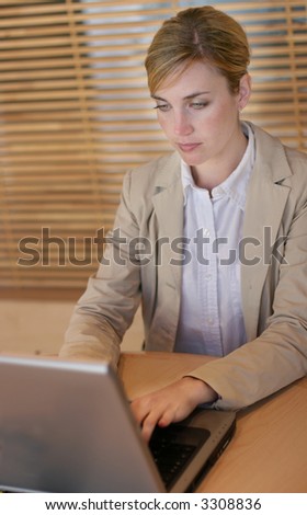 Businesswoman sitting at her table using her laptop getting her work done