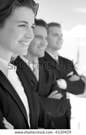 black and white one female two males wearing business suits in a row smiling