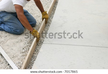 close-up one construction man kneeling holding piece of lumber preparing for concrete