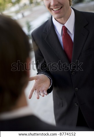 over shoulder view of businessman talking, standing in suit and tie