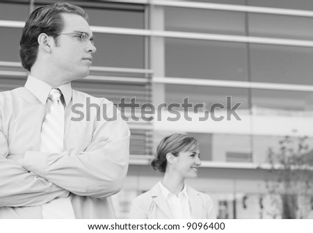 two people standing looking to their left in front of office building