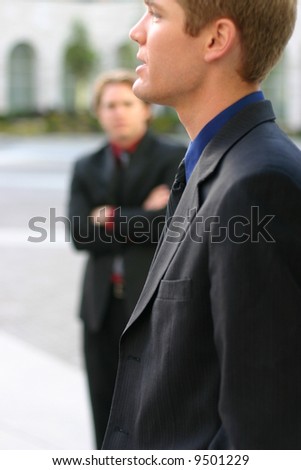 two businessmen standing in full suits