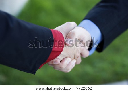 Two Businessmen seal their deal with a Handshake with green grass in the background