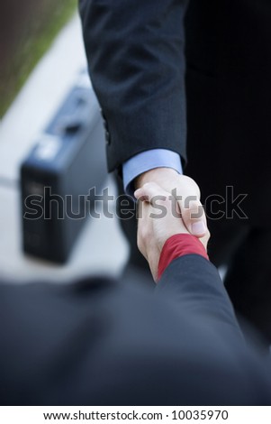 two businessmen standing across from each other shaking hands