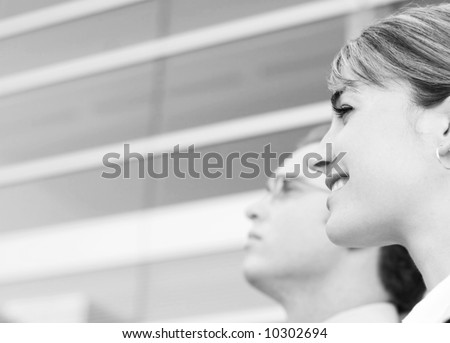 profile view of man and woman standing looking in same direction in front of office building.