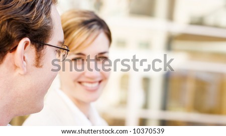 head shot profile view of businessman and businesswoman in front of building