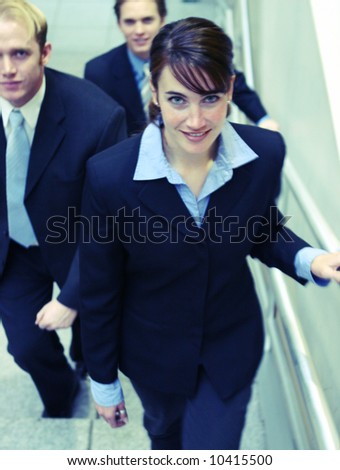 three business people looking towards camera and walking up stairs
