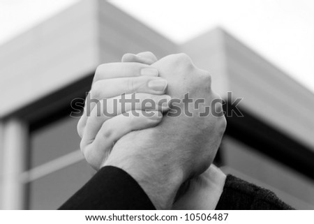 two male hands clasp in front of office building