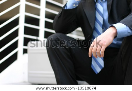 Closeup of businessman sitting on steps in full suit with briefcase by his side