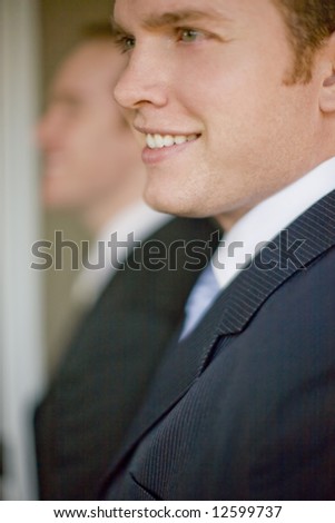 Close up of two businessmen wearing suits smiling in profile view