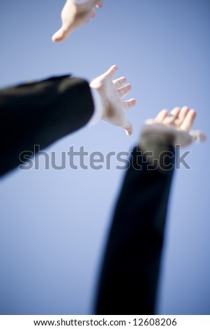 Three business arms and three open hands with blue sky background