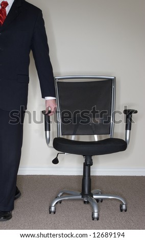 Businessman wearing full suit grabs empty office chair