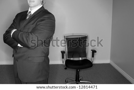 Businessman dressed in full suit standing in front of empty office chair
