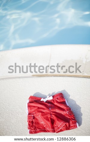 red swimming shorts next to pool of blue water