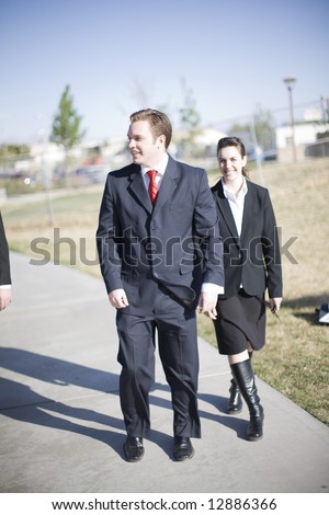 Businesspeople laughing and walking together wearing full suits