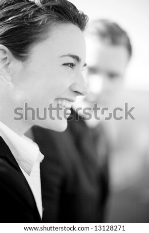 close profile view of attractive young businesswoman standing next to businessman who is looking at her