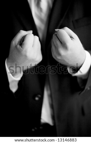 businessman standing in full suit with two clenched fist in front of body