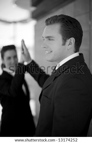 businessman and businesswoman in suits smiling giving high-five
