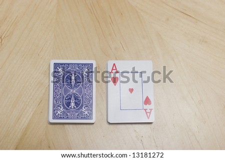 a deck of cards are sitting on a wooden table with the deck split showing an ace of hearts