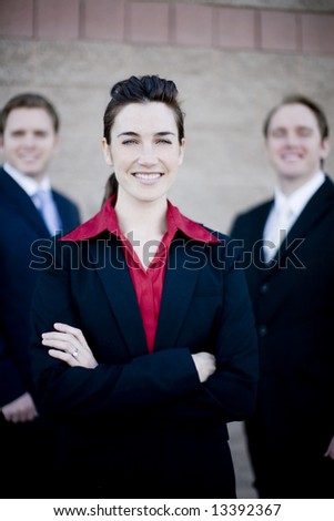 businesswoman standing with two businessmen behind her