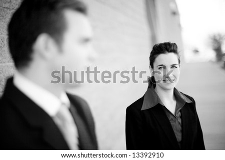 attractive businesswoman and businessman standing looking at each other wearing formal business wear