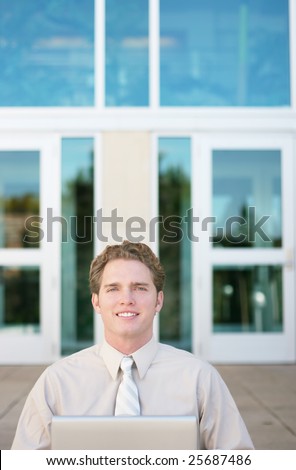 businessman working on his laptop outside the office while sitting and looking ahead