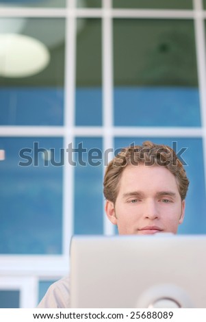 a businessman is looking at and working on his laptop outside