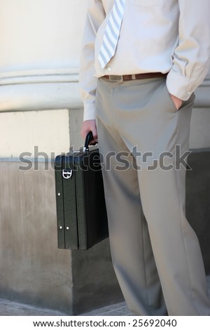 a lawyer is standing next to a column while holding a black briefcase