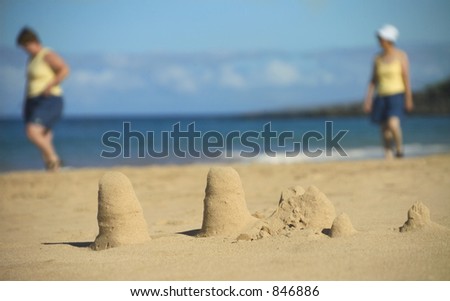 Two women walking behind sand castles