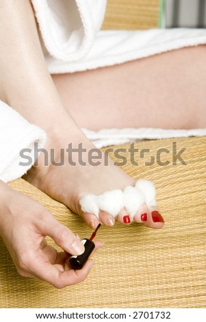 Giving herself a pedicure with red polish