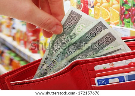 Female hands to get out the money from the purse on the shop background