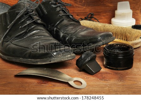 shoe care equipment and formal black shoe on wooden background