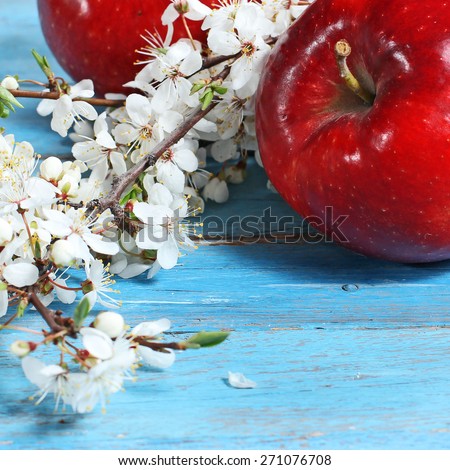 apple flowers and ripe red apples on blue wooden background