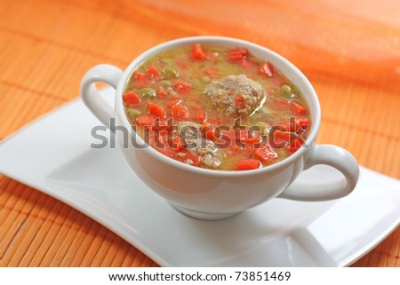 Home-made meatballs and vegetable soup, in a white soup cup